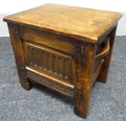 An English joined-oak box-stool with carved facade and twin side handles, 46cms wide