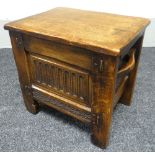 An English joined-oak box-stool with carved facade and twin side handles, 46cms wide