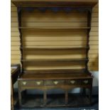 A dark oak dresser with open shelved and boarded base, three drawers and closed rack, circa 1830,