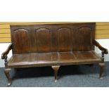 An oak settle with four fielded panels to the slightly angled back and four recesses to the seat,