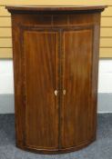 An inlaid and crossbanded-mahogany bow-front corner cupboard with two doors and ribbed-apron