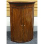 An inlaid and crossbanded-mahogany bow-front corner cupboard with two doors and ribbed-apron