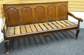 An oak settle, with slanted back having four fielded panels and with pine slats to the seat, circa