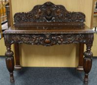 A carved oak serving table, the shaped rail-back and apron featuring heraldic cameo with