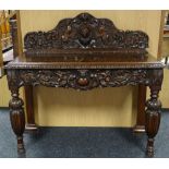 A carved oak serving table, the shaped rail-back and apron featuring heraldic cameo with