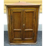 An oak hanging two-door corner cupboard, with two shaped shelves to the interior, 101cms high, circa