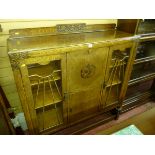 A clean carved oak side by side bureau bookcase with sunburst beaded doors and pineapple supports,