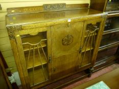 A clean carved oak side by side bureau bookcase with sunburst beaded doors and pineapple supports,