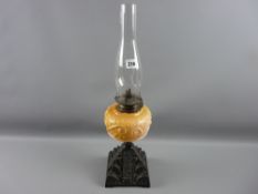 An iron based oil lamp with yellow tinted milk glass reservoir and chimney