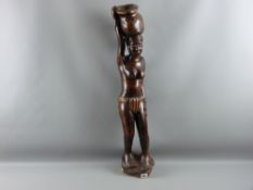 A Mali carved tribal figure of a standing woman carrying a basket upon her head, 80 cms high