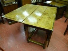 An antique drop leaf dining table with oblong stretchers and turned block supports, 114 cms wide,