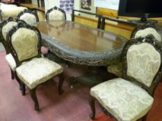 A 20th Century Burmese carved wood dining table on twin carved pedestals, tri-form base and