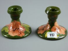 A pair of Moorcroft pottery green ground 'Hibiscus' short stemmed candleholders, 8 cms high