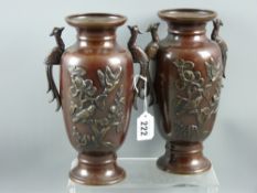 A pair of early 20th Century Oriental bronze vases having twin peacock handles and with raised