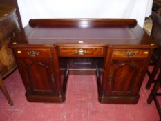 A late Victorian mahogany twin pedestal writing desk with railback, gilt tooled burgundy leather