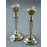 A pair of modern circular based silver table candlesticks having plain tapered columns, 21 cms high,