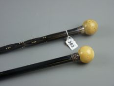 An ebonized walking cane with white metal collar and ivory ball grip, 90 cms and a twisted ebony and