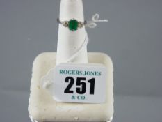 An eighteen carat white gold emerald and diamond dress ring having a centre oblong  cut emerald