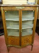 A French style serpentine front Louis XVI type inlaid two door display cabinet with brass