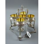 A silver five cup eggstand, the square shaped stand having a double tier with dart decoration, the