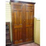 A mahogany two door housekeeper's cupboard with twin inset five panel doors opening to reveal a good