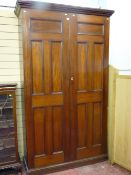 A mahogany two door housekeeper's cupboard with twin inset five panel doors opening to reveal a good