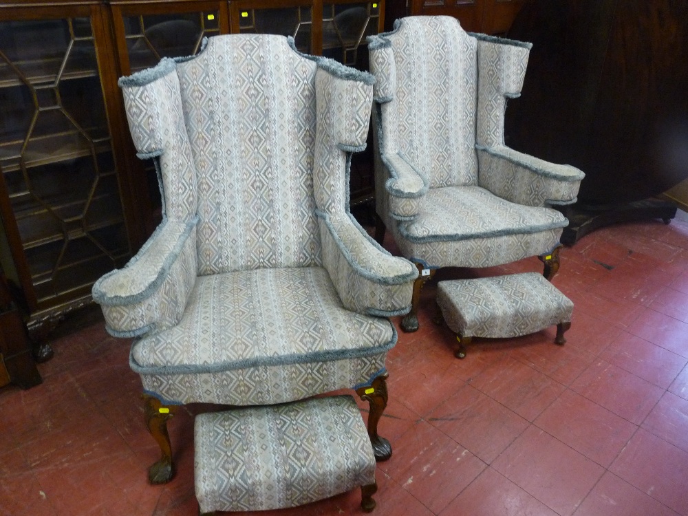 A good quality pair of reproduction walnut wingback armchairs and two footstools in matching