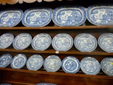The parcel of five Willow patterned pottery platters and eighteen circular plates in two sizes as