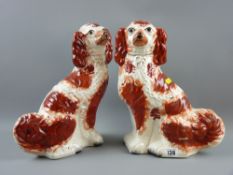 A pair of red and white Staffordshire pottery seated spaniels, circa 1880, 30 cms high