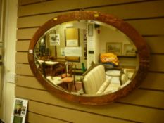 A vintage beaten copper framed oval wall mirror with bevelled edge glass, 59.5 x 86 cms