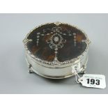 A circular silver ring box on three scrolled supports with fine silver and tortoiseshell lid
