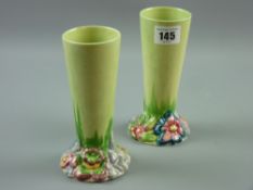 A pair of green ground Clarice Cliff 'Bizarre, My Garden' vases, 15.5 cms high (some paint