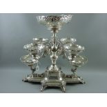 An extremely impressive all silver table centrepiece having a curved square centre base with