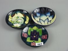 Three Moorcroft pottery 'Indigo', 'Lamia' and 'Violet' pin dishes, 11.5 cms diameters, painted and