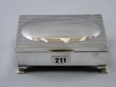 An oblong silver ring box, uninscribed, having corner bracket feet and velvet and silk interior,