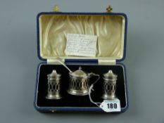 A cased three piece silver condiment set, each piece of pierced capstan form and with Bristol blue
