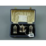 A cased three piece silver condiment set, each piece of pierced capstan form and with Bristol blue