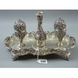 An oblong shaped silver inkstand having a floral and scrolled gallery on four scrolled supports