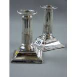 A pair of square based short stemmed Corinthian column silver candleholders having bead edge