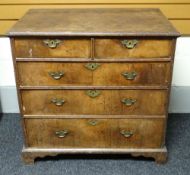 A Georgian oak and walnut veneer chest of three long and two short drawers, on bracket feet and with