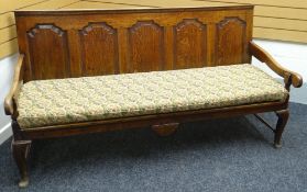 An oak settle, with slanted back having four fielded panels and with pine slats to the seat, circa