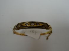 A 15ct yellow gold four stone diamond bangle, the centre stone being 0.35ct visual estimate, 9.9gms