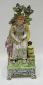 An early nineteenth century Staffordshire seated figure with child and foliage on a raised base,