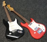 A black and white Encore electric guitar and another red and white unnamed