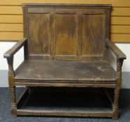 A rustic oak settle, having a tri-panelled back and twist-carve decoration to the supports, circa