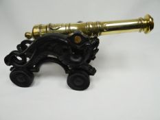 A brass signalling cannon with painted cast iron wheeled carriage depicting dragons