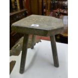 An antique oak three legged milking stool, the front of seat with canted corners, 33 cms high