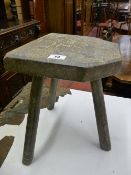 An antique oak three legged milking stool, the front of seat with canted corners, 33 cms high