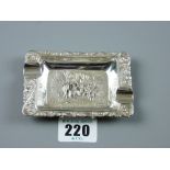 A Continental white metal oblong ashtray with floral border and panel of figures to the centre at