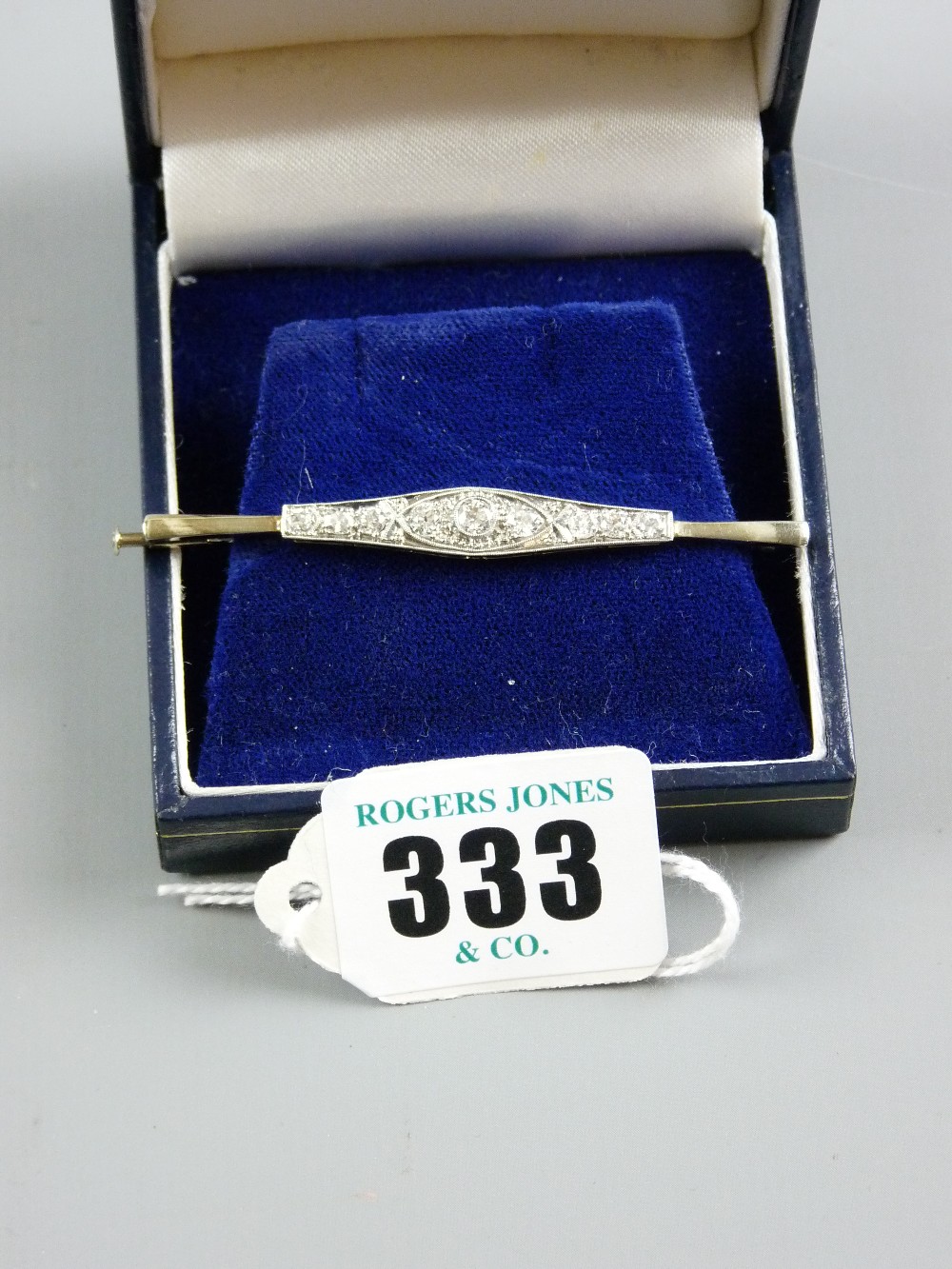 An eighteen carat platinum oblong bar brooch, the shaped bar having a centre round cut diamond,